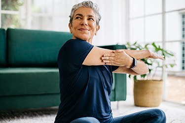 Senior woman smiling while stretching at home