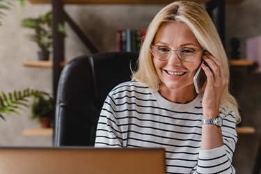 Woman with glasses smiling while talking on phone