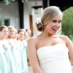 Smiling woman in wedding dress with bridesmaids behind her