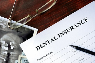 Dental insurance form sitting on a desk next to glasses