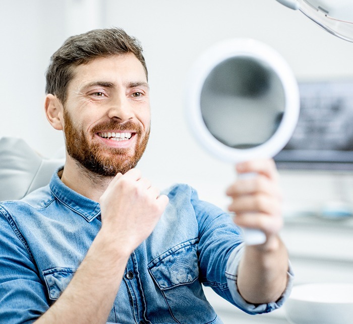 a patient checking his smile with a mirror