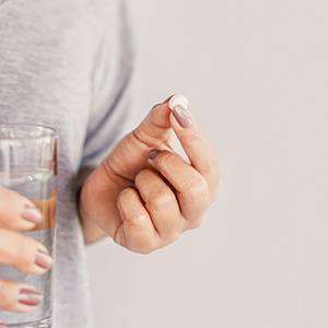 Woman holding a pill and water