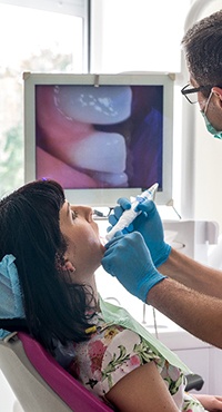 dentist using an intraoral camera on a patient and looking at the image