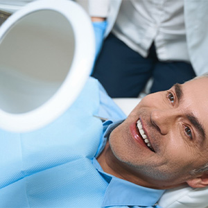 Dental patient looking at his new smile in a mirror