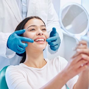 Young woman smiling at reflection in handheld mirror