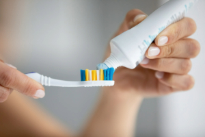 Squeezing toothpaste onto toothbrush